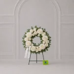 A small circular sympathy wreath featuring approximately 18 white roses
